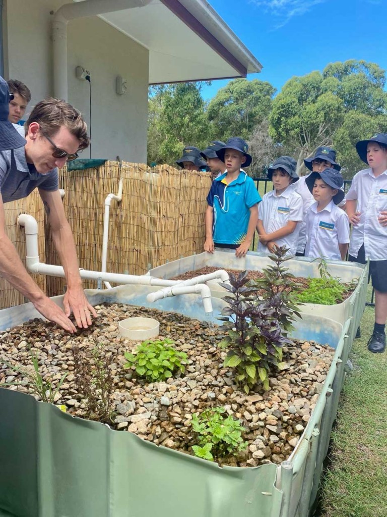 Mr. Wright showing students how the garden beds water level rises and lowers